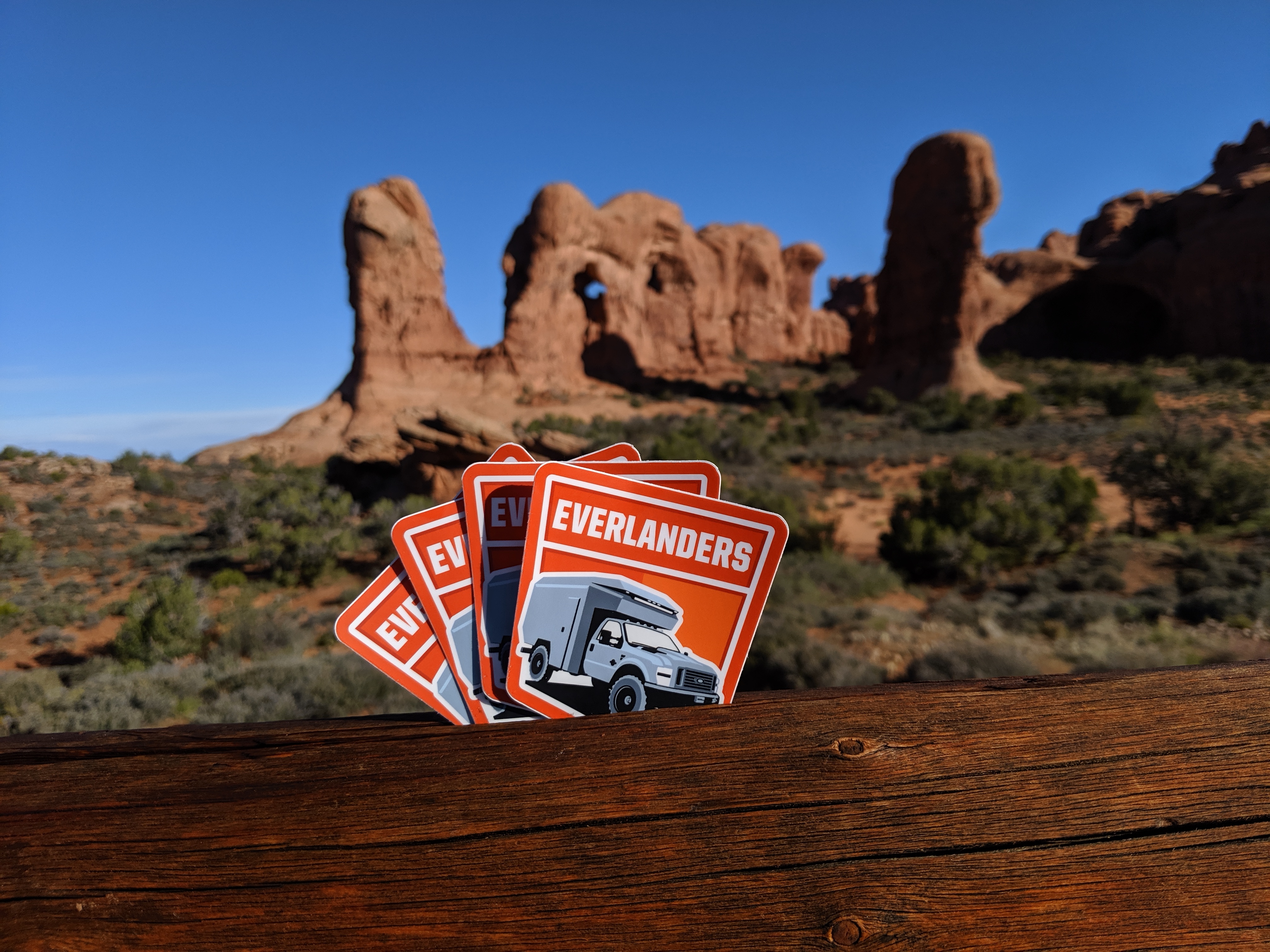 Stickers with the text 'EVERLANDERS' prominently displayed in the foreground, with a scenic landscape of red rock formations and blue sky in the background.