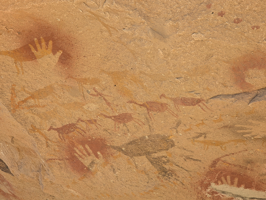 Ancient cave paintings depicting handprints and animals on a rock surface.