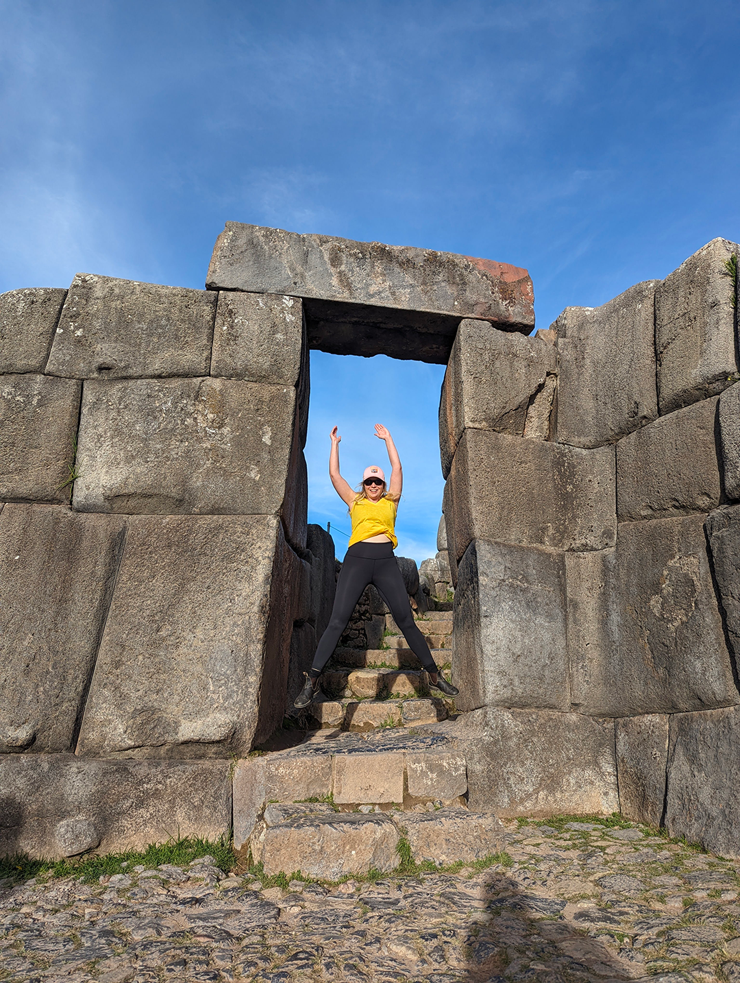 Kara jumping in a doorway made of large stone blocks, with a blue sky in the background.